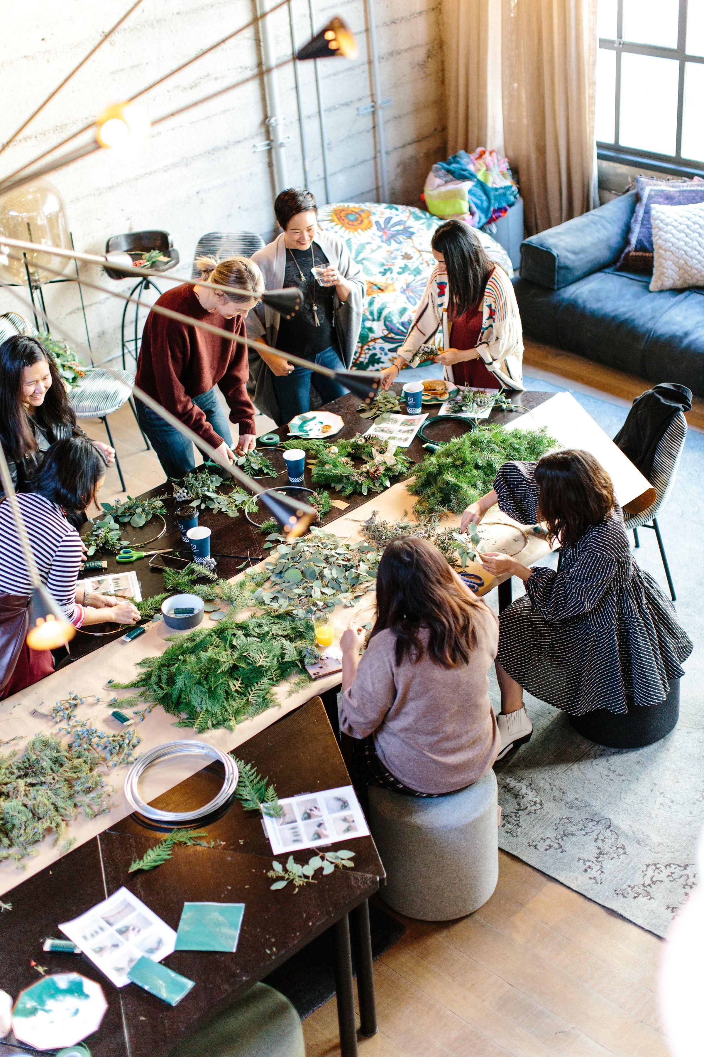 group of six people around a table building a project together with a office and background